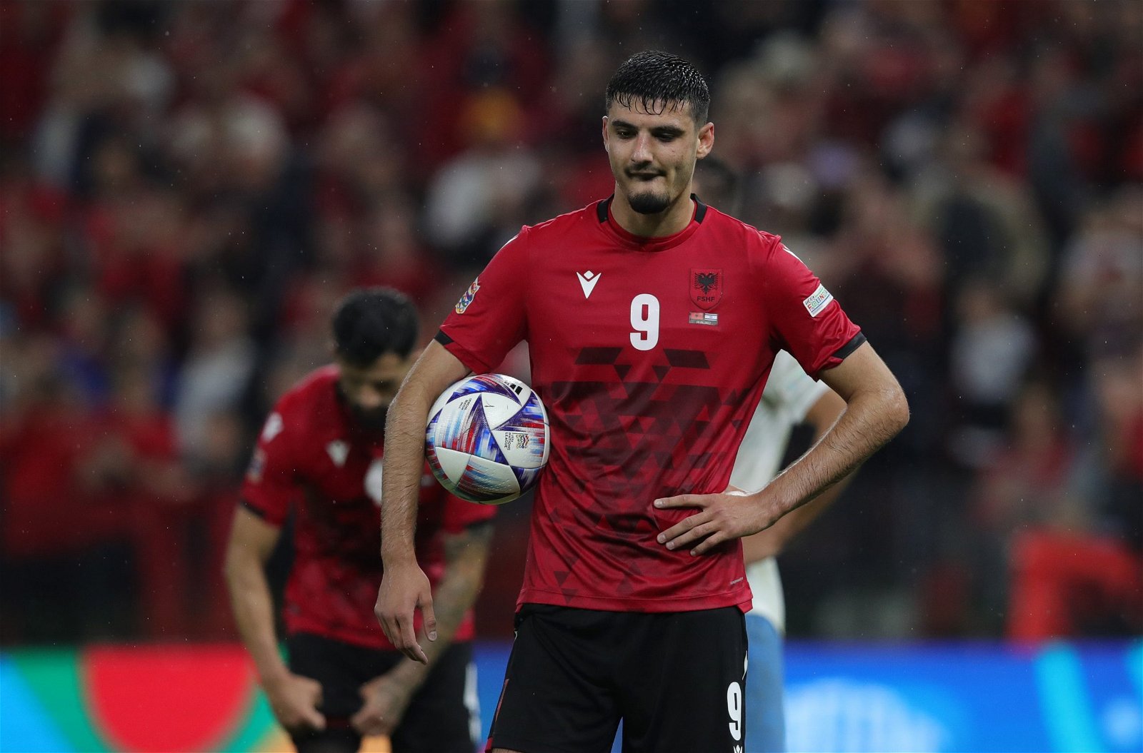  Armando Broja, wearing a red Albania uniform with the number 9, looks on during a soccer match.